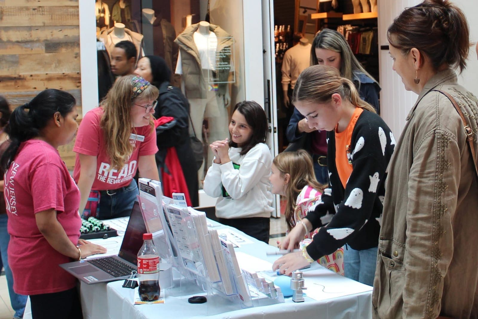 Families connect with library staff at a community outreach table.